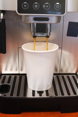Kağıt bardağa dökülen taze espresso. Otomatik makine. Zengin kremalı, paslanmaz çelik damlatma tepsisi ve sıcak arka ışıklandırma.