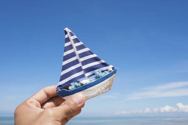 Model boat on sandsea with blue sky background