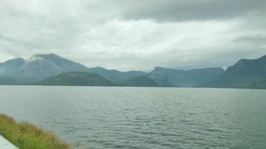 Hindistan 'ın Tamil Nadu kentindeki Aliyar Barajı' ndaki bir göl bulutlu gökyüzünün altındaki yeşil tepeleri yansıtır. Yumuşak dalgalar ve durgun su sakin bir doğal manzara yaratır.