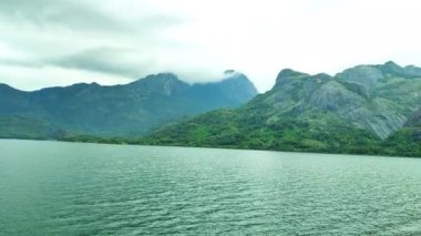 Hindistan 'ın Tamil Nadu kentindeki Aliyar Barajı' nda yeşil tepeler ve bulutlu bir gökyüzünün altındaki kayalık tepelerle çevrili bir göl. Doğa, seyahat ve açık arazi temaları için idealdir..