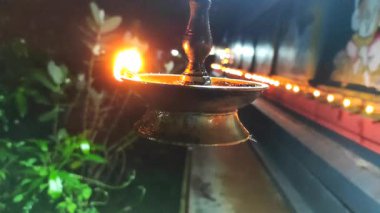 Geleneksel bir pirinç gaz lambası gece Palakkad, Kerala, Hindistan 'da bir Şiva tapınağında sicim ışıkları ve yeşillikle çerçevelenmiş, manevi ambiyansı, kültürü ve kutsal geleneği yansıtan sıcak bir şekilde parlar..