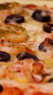 Zeytin ve otlarla kaplı taze pişmiş karidesli pizzanın yakın çekimi ağız sulandırıcı tatlar sergiliyor. Aile yemeği ya da arkadaşlarla bir araya gelmek için mükemmel..