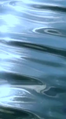 Pürüzsüz su yüzeyinde parıldayan güneş ışığı, huzurlu bir çevrede güzel yansımalar yaratır. Doğa bu öğle saatinde canlı ve huzurlu hissediyor..