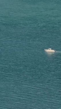 Küçük bir tekne gölün pürüzsüz yüzeyinde sessizce süzülür. Açık mavi su etrafındaki ağaçları ve gökyüzünü yansıtır. Doğada huzurlu bir an..