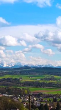 Bahar mevsimi boyunca dağların, yuvarlanan yeşil tarlaların ve parlak mavi gökyüzünün altında kabarık bulutların bulunduğu çarpıcı bir manzara keşfedin. Doğa güzelliği ışıldıyor.