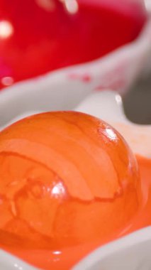 Parlak turuncu yumurtalar dikkatlice boyanır ve bir mutfakta sergilenir. Bahar kutlaması için canlı renkler sergilenir. Süreç yaratıcılık ve geleneği vurguluyor.