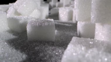 Bu yakın plan beyaz şeker küpleri ve granüllerin karmaşık desenlerini ve dokularını yakalar. Büyüleyici şekillere ve parlak gölgelere bak..
