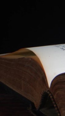 Sayfaları yavaşça dönerken eski bir kitabın ayrıntılı görünümü. Ilık aydınlatma, edebiyat ve tarihin güzelliğini ortaya çıkararak dokuları ve renkleri geliştirir..