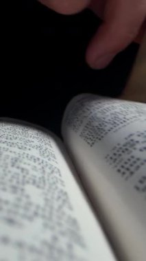 Bir el, ayrıntılı metinlerle dolu bir kitabın sayfasını nazikçe çevirir. Sıcak ışık sıcak bir atmosfer yaratıyor, içerideki kelimelere odaklanmamızı sağlıyor..