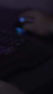 Bir oyuncu renkli LED ışıklarla dolu loş bir odada fare ve klavye kullanarak yoğun bir oyun oturumuna katılır. Konsantrasyon ve beceri gösteriyor..