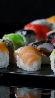 Suşi parçaları renkli bir tabakta sergilenir. Taze malzemeler ve dikkatli sunum bu ziyafeti davetkar gösteriyor. Dostlar bu lezzetli yemeği paylaşmak için toplandı..