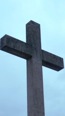 Katı bir taş haç, yumuşak bulutlardan oluşan bir zemin ve bulutlu bir gökyüzüne karşı yükselir ve barışçıl bir atmosfer yaratır. Ayarlar bir sakinlik ve yansıma hissi uyandırıyor..