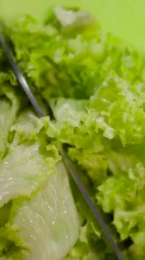 Taze, taze marul güneşli bir mutfakta keskin bir bıçakla dilimleniyor. Canlı yeşiller salata için hazır, her yemek için sağlıklı bir seçenek sunuyor..