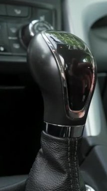 Modern bir araba vitesindeki vites değişiminin yakın çekim görüntüsü kullanıcı sürmeye hazırlanırken parlak tasarım ve kaliteli malzemeler sergiliyor. Detaylara dikkat etmek otomotiv içindeki lüksü yakalar..