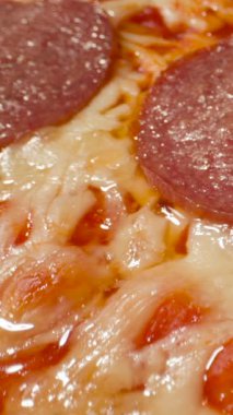 Sıcak bir mutfakta, taze yapılmış bir pepperoni pizzası köpüklü peynir ve mükemmel pişirilmiş pepperoni dilimleri ile gösterilir. Zengin tatlar davetkar ve ağız sulandırıcı..