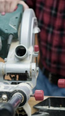 Bir zanaatkar atölyede elektrikli testere kullanır, yeni mobilya yapmak için ustalıkla odun keser. Parlak öğleden sonra ışığı projenin detaylarını arttırır..