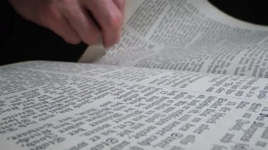 Bir el, kütüphanedeki eski bir kitabın sayfalarını nazikçe çevirir. Yağmur damlalarının rahatlatıcı sesi dışarıda duyulabilir, okuma ve düşünme için sakin bir atmosfer yaratır..