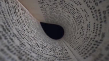 Eski bir kitabın eşsiz bir perspektifini keşfedin. Sayfaları içe doğru kıvrılır, metnin karmaşık detaylarını ve eskimiş edebiyatın güzelliğini gösterir..