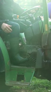 Yeşil çizmeli bir çiftçi, sabahın erken saatlerinde tarlada çalışmak için traktöre biner. Sahne, kırsal yaşamı ve tarımı yakalıyor..