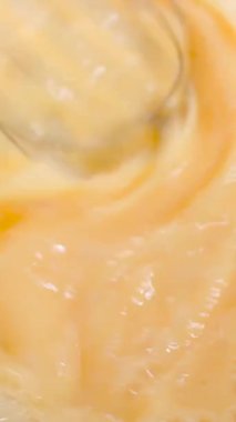 Hamur pişirmek için çırpılmış yumurtaları yakından çek. Pürüzsüz, altın dokular ve yumuşak ışıklandırma lezzetli ve iştah açıcı bir görünüm yaratır. Yemek pişirme dersleri, yemek pişirme videoları, yemek tarifleri ve...