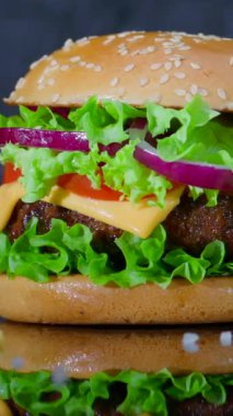 Bu klip lezzetli bir sandviçin hazırlanmasını gösteriyor. Salatanın, peynirin, domateslerin ve soğanların sulu bir böreğin üzerindeki canlı katmanlarını vurguluyor..