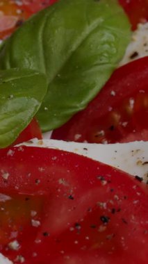 Taze mozzarella peyniri olgun domatesler ve aromatik fesleğenlerle kaplıdır. Bir tutam tuz ve biber bu lezzetli yemeğin tadını arttırır..
