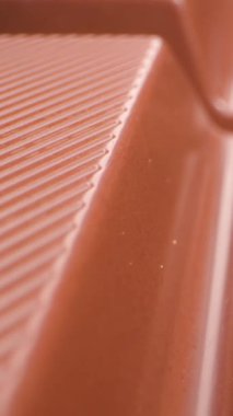 Yumuşak yüzeyini ve ince dokusunu ılık doğal ışık altında gösteren bir sütlü çikolatanın detaylı makro görüntüsü. Odak, zengin kahverengi tonları ve parlak sonu vurguluyor. Lezzetli bir son yaratıyor.