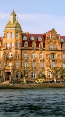 Video, su kenarındaki tarihi bir oteli çekiyor. Günbatımının sıcacık parıltısı zarif mimariyi ve sakin atmosferi vurguluyor. İnsanlar suyun yanında vakit geçiriyorlar..