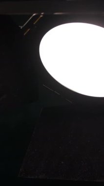 Bir fotoğraf stüdyosunda, etrafındaki karanlık yüzeyleri aydınlatan yuvarlak, parlak bir aydınlatma armatürü kurulur. Görüntüleri yakalamak için mükemmel ışıklandırma koşulları oluşturuluyor..