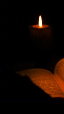 Gölgeler odada dans ederken, mum ışığı açık bir kitabı aydınlatır. Rahatlamak ve gece boyunca düşünmek için mükemmel sakin bir ortam yaratır..