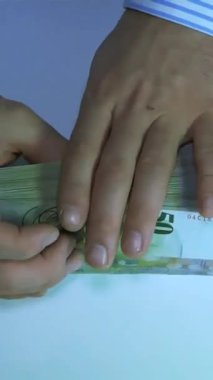 Eller ustalıkla sayılıyor ve büyük bir para yığını düzenleniyor. Parlak arka plan paranın detaylarını ve sayma tekniğini vurgular..