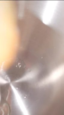 Çiğ yumurtanın paslanmaz çelik bir kaseye düşüşünü yakından çek. Çarpışma anında yumurta beyazı ve sarısı parlak metal yüzeyde yayılır. Yemek pişirme dersleri ve yemek tarifi için ideal