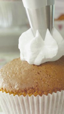 Bir fırıncı, neşeli bir mutfakta yeni pişmiş bir kekin üzerine dikkatlice borular döker. Süreç, çok iyi dekorasyon teknikleri sergiliyor ve lezzetli bir ziyafetle sonuçlanıyor..