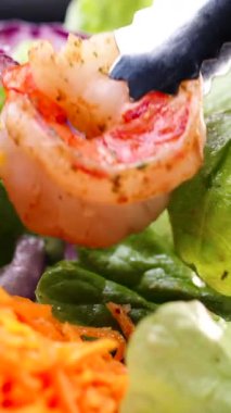 Aşçı lezzetli bir karides salatası hazırlar taze sebzeler ve renkli sebzeleri sıcak bir mutfakta birleştirir. Süreçte canlı malzemeler ve aşçılık becerileri sergileniyor.