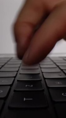 Dizüstü bilgisayarın klavyesinin kenarından başlayan ve eller görünüp yazmaya başlarken öne doğru kayan pürüzsüz bir kamera hareketi. Çekim, dinamik parmak hareketini ve modern bilgisayar donanımını gösteriyor.