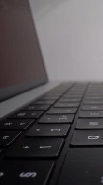 Anahtarları ve yüzeyi ayrıntılı olarak gösteren bir dizüstü bilgisayar klavyesi boyunca düzgün bir kamera hareketi. Çekim, teknoloji sunumları için uygun modern bilgisayar tasarımı dijital çalışma alanı temaları ve