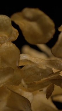 Pürüzsüz, yavaş çekimde havaya atılan altın gevrek cipsleri yakın çekim. Yüzen atıştırmalıklar, dokuyu ve hareketi vurgulayan etkileyici bir dinamik sahne yaratıyor. Gıda içeriği için ideal