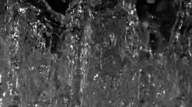 Su enerjiyle sıçrar, çarpıcı şekiller ve desenler yaratır. Yakın plan görüntüsü, damlacıkların karanlık bir zemin, sergilenen doğaya karşı berraklığını ve hareketini vurguluyor..