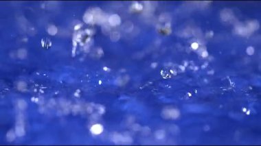 Yağmur damlaları durmaksızın düşer, parlak mavi su yüzeyinde dalgalanmalar yaratır. Suyun sesi yağmurlu günün huzurlu atmosferini güçlendirir..