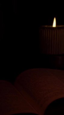Açık bir kitabın sayfalarını aydınlatan yumuşak mum ışığı yanıp sönerken huzurlu bir okuma gecesinin tadını çıkarın. Sessiz atmosfer rahatlamayı ve yansımayı davet eder..