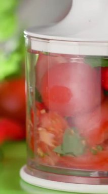 Taze domates ve bitkiler lezzetli bir salsa yapmak için temiz bir kabın içinde doğranır. Mutfak canlı ve davetkar. Etrafı renkli malzemelerle çevrili..