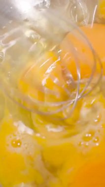 Taze yumurtalar bir kase içinde çırpılıp lezzetli bir omlet yapmak için karıştırılıyor. Bu etkinlik sıcak bir mutfakta gerçekleşiyor..