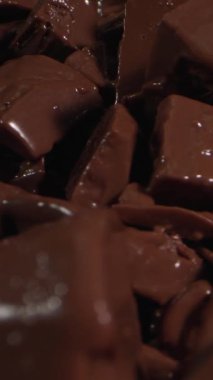 Lezzetli çikolata parçaları sıcak bir mutfakta yavaşça eriyor ve kremalı bir doku yaratıyor. Pişirmek için mükemmel. Keyifli bir ikram için dönüşümü izleyin..