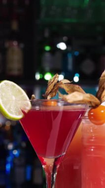 Karışım sanatını canlı bir kokteyl olarak tecrübe etmek taze limon ve eşsiz süslemelerle yapılır. Arkaplanda renkli içeceklerle dolu canlı bir bar atmosferi var..