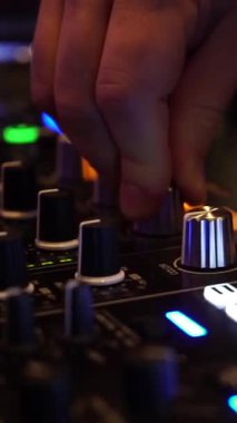 Bir DJ, mikser kontrollerini yanıp sönen ışıklarla dolu canlı bir kulüpte ayarlar. İnsanlar eğlenirken, dans ederken ve eğlenirken, ritim darbeleri.