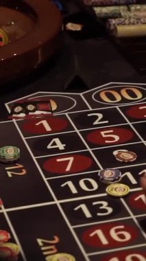 Oyuncular bahislerini renkli çipler ve rakamlarla dolu bir rulet masasına yatırırlar. Dönen tekerleğin sonucunu tahmin ettiklerinde heyecan havayı dolduruyor..