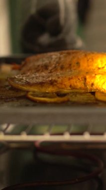 Sıcak bir fırında taze bir somon filetosu rengarenk sebzelerle birlikte pişiriliyor. Sıcak bir mutfak atmosferinde aromatik tatlar yayıyor..