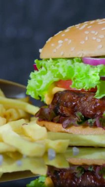 Lezzetli bir hamburgerin yanında sulu biftek köftesi, taze marul, domates ve soğan, ahşap tabakta çıtır altın patates ile servis edilir..