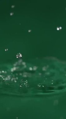 Damlacıklar yeşil bir yüzeye düşerek dalgalanan ve ışığı yansıtan canlı sıçramalar yaratırlar. Her sıçrama, su dinamiğinin güzelliğini gözler önüne sererek ayrıntılı olarak kaydedilir..