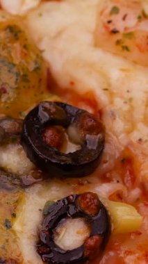 Siyah zeytin ve baharatla kaplı bir tabak erimiş peynir kıyı kasabasında bir yaz öğle yemeğinde servis edilir. Arkadaşlar dinlenirken sıcak yemeğin tadını çıkarırlar..